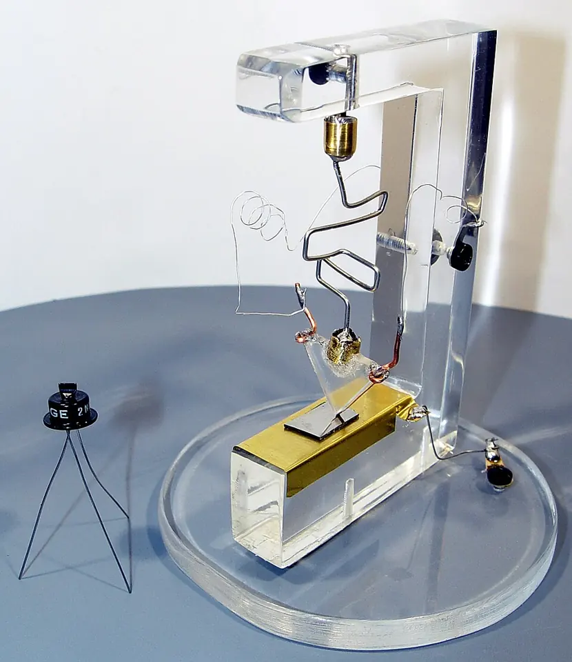 Réplique du premier transistor à avoir fonctionné. Le petit composant sur pied, à gauche, est un transistor plus récent, du type 2N43, placé à côté pour comparer les tailles.